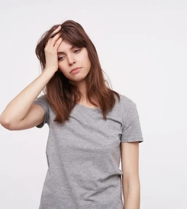 indoor-shot-young-pretty-brunette-female-holding-raised-hand-her-head-looking-tiredly-down-while-standing-white-background-casual-clothes-scaled ¿SOP y estrés? Busca ayuda de una nutricionista experta en SOP
